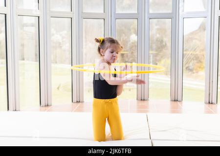 Piccola ragazza bionda con code piggy che gioca con hula hoop Foto Stock