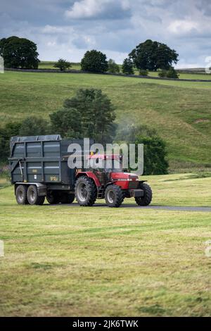 Trattore Case International 5140 4x4 che traina un rimorchio per insilato in un campo, Cumbria, Regno Unito. Foto Stock