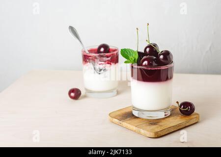 Dessert di gelatina. Yogurt e gelatina di ciliegia su sfondo chiaro. Foto Stock