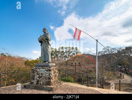 nagasaki, kyushu - dicembre 14 2021: Bandiera della compagnia di navigazione Kaientai a lato di una statua del suo fondatore il samurai Sakamoto Ryōma indossando kimono e katana Foto Stock