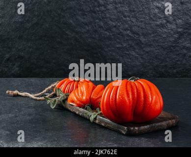 Un gruppo di grossi pomodori Costoluto con origano su sfondo grigio, spazio per il testo Foto Stock