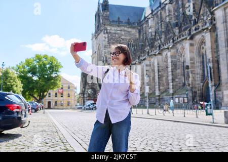 Donna turistica che prende un selfie di fronte ad un'antica cattedrale europea Foto Stock