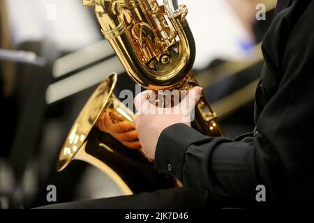 Un primo piano delle mani di un musicista che suona un sassofono baritono. Foto Stock