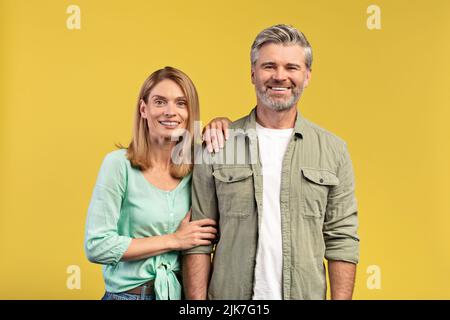 Coppia matura romantica. Ritratto di felice uomo e donna europeo di mezza età in posa su sfondo giallo Foto Stock