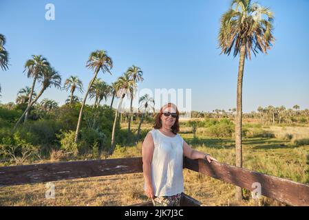 Donna ispanica matura in un punto di vista nel Parco Nazionale di El Palmar, in Entre Rios, Argentina, un'area protetta dove si trova l'endemica palmtree di Butia yatay Foto Stock