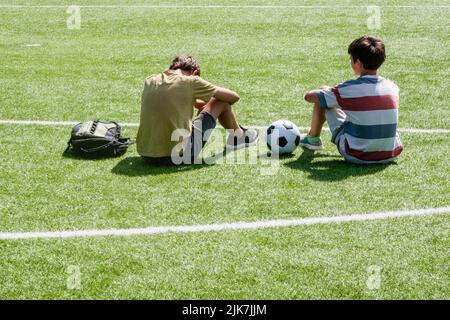 I bambini parlano allo stadio della scuola all'aperto. Ragazzo adolescente confortante consolante sconvolto triste amico. Educazione, intimidazione, conflitto, relazioni sociali Foto Stock