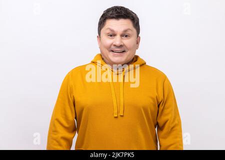 Ritratto di bell'uomo di mezza età con capelli scuri in piedi guardando la fotocamera con il volto soddisfatto e sorridente, indossando una felpa con cappuccio urban style. Studio interno girato isolato su sfondo bianco. Foto Stock