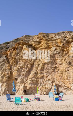 Sagres, Portogallo. 22nd luglio 2022. Sedie pieghevoli e ombrelloni chiusi si trovano di fronte ad un muro di roccia presso la spiaggia 'Praia do Beliche'. Credit: Viola Lopes/dpa/Alamy Live News Foto Stock