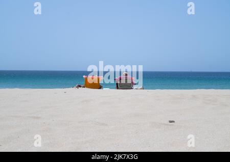 Sagres, Portogallo. 22nd luglio 2022. Beach goers seduti su sedie al sole su una spiaggia in Algarve. Credit: Viola Lopes/dpa/Alamy Live News Foto Stock