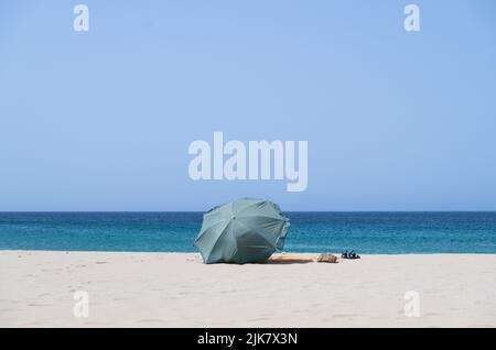 Sagres, Portogallo. 22nd luglio 2022. Un ombrellone verde è bloccato nella sabbia su una spiaggia dell'Algarve. Credit: Viola Lopes/dpa/Alamy Live News Foto Stock