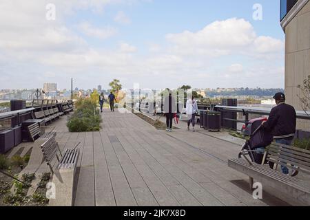 New York, NY, USA - 1 agosto 2022: Persone che camminano sulla High Line sopra 30th Street guardando verso ovest verso lo skyline del New Jersey Foto Stock