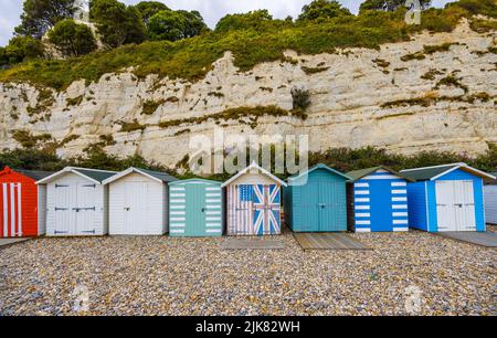 Una fila di capanne sulla spiaggia ai piedi delle scogliere di gesso a Beer, un piccolo villaggio costiero sulla baia di Lyme nella Jurassic Coast of East Dorset, sud-ovest Inghilterra Foto Stock