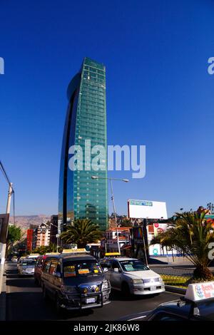 Veicoli in attesa al semaforo con la nuova Torre Verde / grattacielo Torre Verde sullo sfondo, Av Ballivian, Calacoto, la Paz, Bolivia. La Green Tower è stata completata nel 2022 e con 46 piani è attualmente l'edificio più alto della Bolivia. Si tratta di un progetto e di un investimento della Compañía de Inversiones Comversa S.A. e dell'uomo d'affari e politico boliviano Samuel Doria Medina. L'edificio contiene uffici e appartamenti. Foto Stock