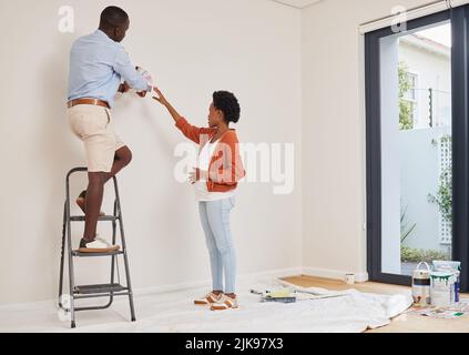 Che colore ti piace. Scatto a tutta lunghezza di una giovane coppia utilizzando campioni di colore per decidere un colore per la loro stanza a casa. Foto Stock