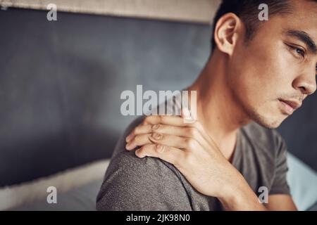 Questo materasso potrebbe essere il colpevole. Un giovane che sperimenta dolore alla spalla dopo essersi svegliato a letto a casa. Foto Stock