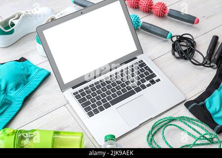 Moderno computer portatile in struttura composto da diverse attrezzature sportive su sfondo di legno chiaro Foto Stock