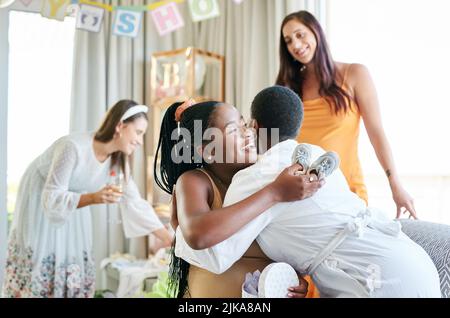 Im così grato per voi. Una giovane madre che abbraccia il suo amico per un regalo dato al suo acquazzone del bambino. Foto Stock