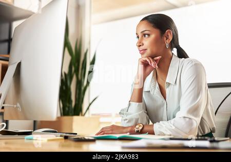 Finalmente questa e-mail è stata inviata. Una giovane donna d'affari che usa il suo PC desktop al lavoro. Foto Stock
