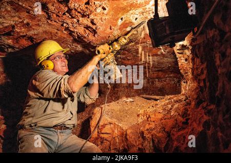 Grahame McMahon, pensionato il clergyman anglicano ora opale minatore sotterraneo nella sua miniera a Lightning Ridge Foto Stock