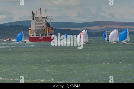 Solent, Inghilterra meridionale, Regno Unito. 2022. Settimana di Cowes e yacht da corsa vicino alla nave portaerei Eli A sul Solent con uno sfondo se l'isola o Foto Stock