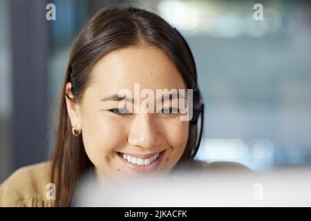Shes un rappresentante di servizio clienti stellare. Una giovane donna d'affari che usa un calcolatore mentre lavora in un call center. Foto Stock