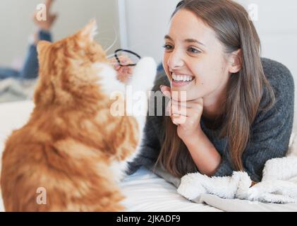 Godendo una giornata pigra con il suo amico più lontano, una giovane donna che gioca con il suo gatto a casa. Foto Stock