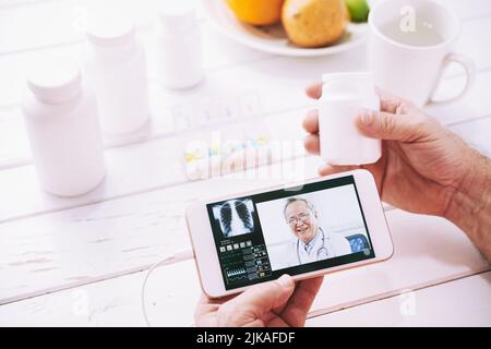 Mani di un paziente anziano che consulti il medico generico online sul suo smartphone Foto Stock