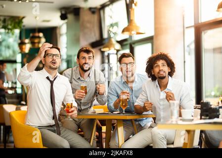 Vecchi amici allegri che si divertono e bevono birra alla spina al tavolo del bar nel pub. Foto Stock
