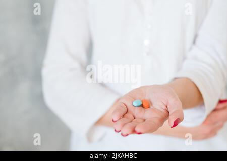 donna mano due pillole dolore farmaco salute Foto Stock