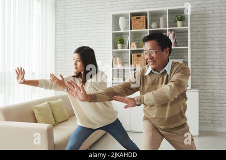 Madre e padre che si godono thai chi pratica a casa Foto Stock
