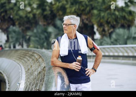 Sportivo senior che beve acqua fresca dopo la corsa Foto Stock