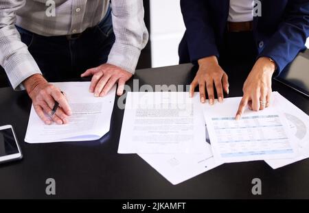 Shes felice con la sua situazione finanziaria. Colpo ad angolo alto di un mediatore femminile irriconoscibile ed il suo cliente maschio che passa sopra un certo lavoro di ufficio nella sua sede. Foto Stock