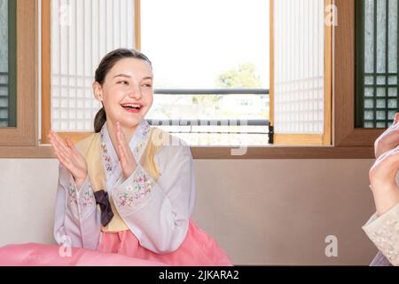 Ragazze coreane e caucasiche che indossano Hanbok giocando a YUT, gioco da tavolo tradizionale coreano Foto Stock