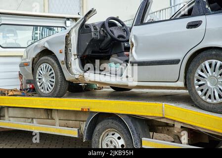 Carico di un'auto distrutta su un autocarro trainato dopo un incidente stradale, concetto di guida pericolosa dopo aver bevuto alcol, concetto di assistenza stradale Foto Stock