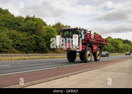 Coltivatori trattore di irrorazione delle colture che viaggia lungo la circonvallazione sud a Norwich Norfolk Foto Stock