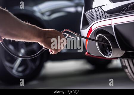 Misurazione delle emissioni di gas di scarico nella stazione di ispezione tecnica. Un riparatore di auto applica una sonda allo scarico. Foto Stock