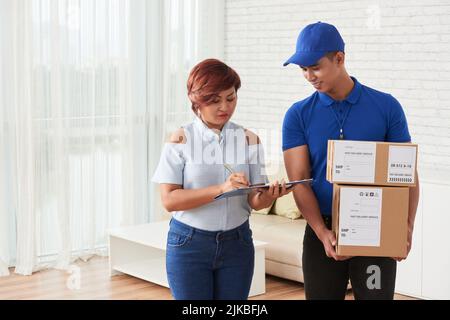 Donna vietnamita firma documento di consegna dopo aver ricevuto i pacchi Foto Stock