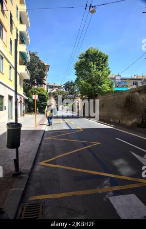 Strada con edifici alti e un muro di pietra in una giornata limpida Foto Stock