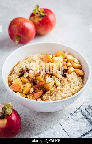 Fiocchi d'avena autunnali con mela caramellata e cannella in ciotola bianca. Ricetta invernale accogliente. Cibo sano e confortevole. Foto Stock