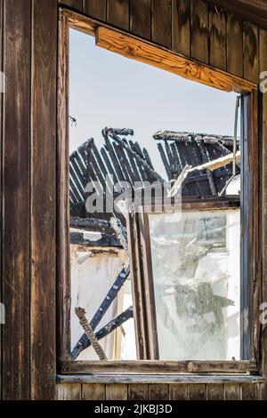 I resti della casa bruciata. Rovinato e crollato casa bruciato e danneggiato nel fuoco con resti di legno di rinforzo pali di tetto selezionare Foto Stock