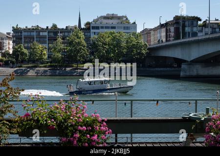 Barca di polizia ('Polizei') che accelera sul fiume Reno verso il ponte Johanniter ('Johanniterbrücke') a Basilea, lasciando un'onda di poppa Foto Stock