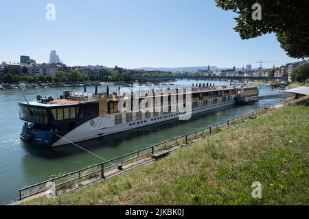 Paesaggio urbano della città svizzera di Basilea con la nave da crociera Amamora ormeggiata sul lungofiume del Reno in primo piano e Ponte Johanniter Foto Stock