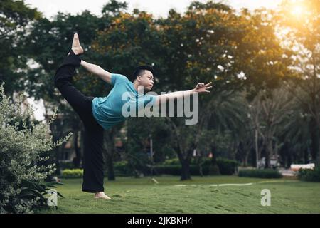 Bel giovane vietnamita che pratica yoga all'aperto Foto Stock