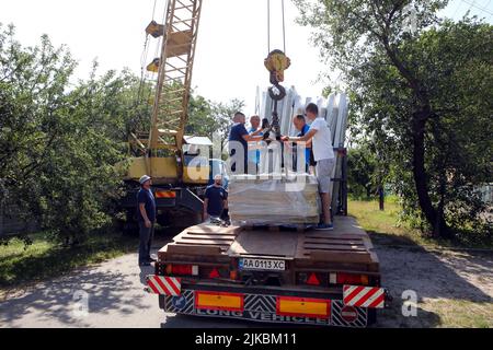 KYIV REGIONE, UCRAINA - 31 LUGLIO 2022 - Volontarii dagli Stati Uniti scaricano i pezzi che formeranno il telaio di una casa modulare per Olena Shevchuk e lei Foto Stock