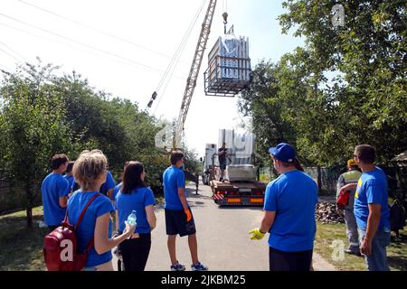 KYIV REGIONE, UCRAINA - 31 LUGLIO 2022 - Volontarii dagli Stati Uniti scaricano i pezzi che formeranno il telaio di una casa modulare per Olena Shevchuk e lei Foto Stock