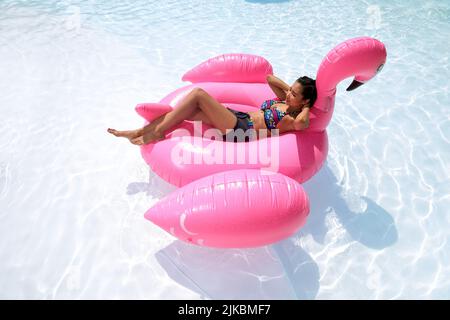 Bella giovane donna vietnamita galleggiando su flamingo gonfiabile Foto Stock