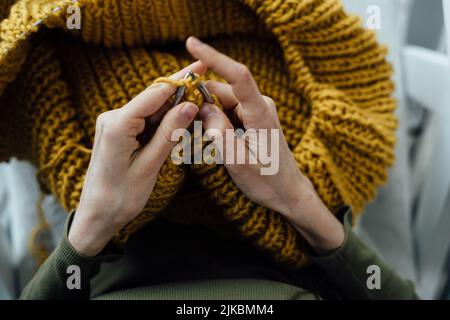 Primo piano del maglione di lana per maglieria femminile a mani. Donna si maglia da filo spesso. Abiti fatti a mano. La ragazza entra per i suoi hobby. Concetto di Unione. Foto Stock