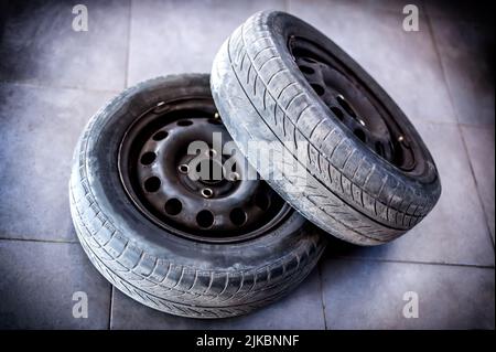 Due pneumatici per auto usate con ruote sul pavimento grigio dell'officina Foto Stock