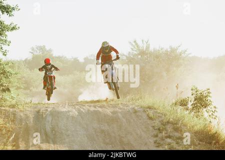 Sportivi professionisti e junior, allenamenti motociclistici in moto nelle calde giornate estive, all'aperto. Pilota di motocross in azione. Motocross sport Foto Stock