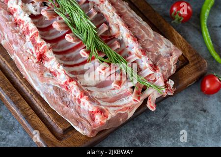 Costolette di agnello. Tritare di agnello fresco intero o costolette su sfondo scuro. Prodotti macellaio. Primo piano Foto Stock